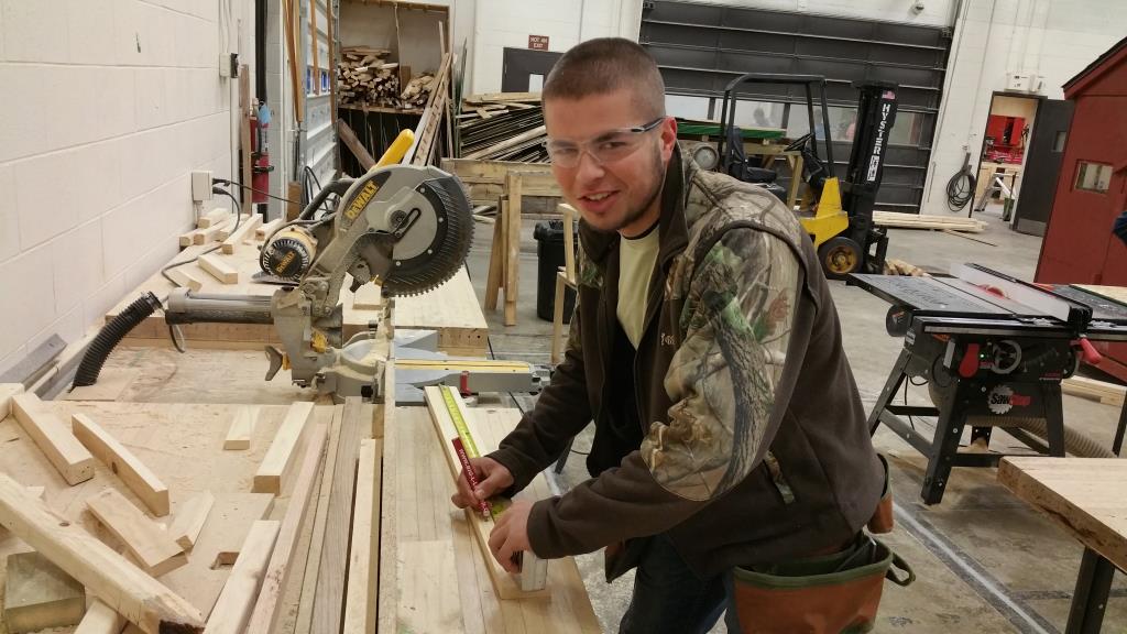A construction student cutting materials for a project.