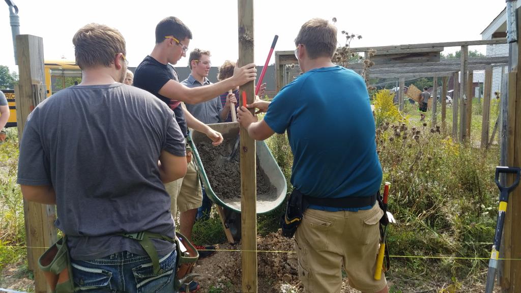 Students cementing in a post for the fence.