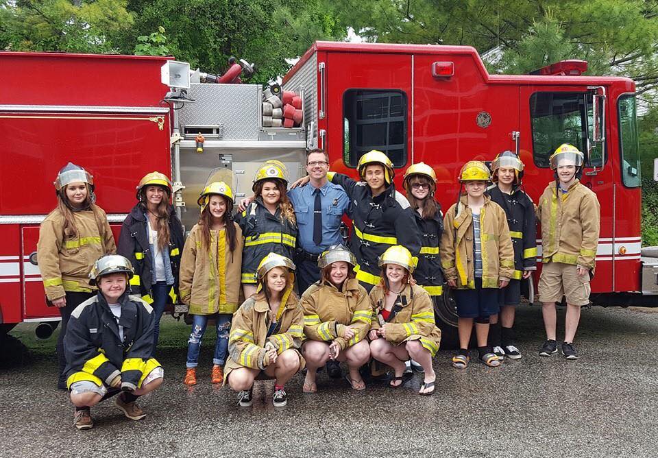 The criminal justice class dressed in fire gear in front of a fire truck.