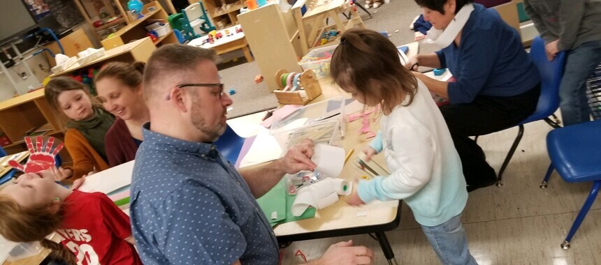 Picture of Dan Brant in a classroom working with a young student.
