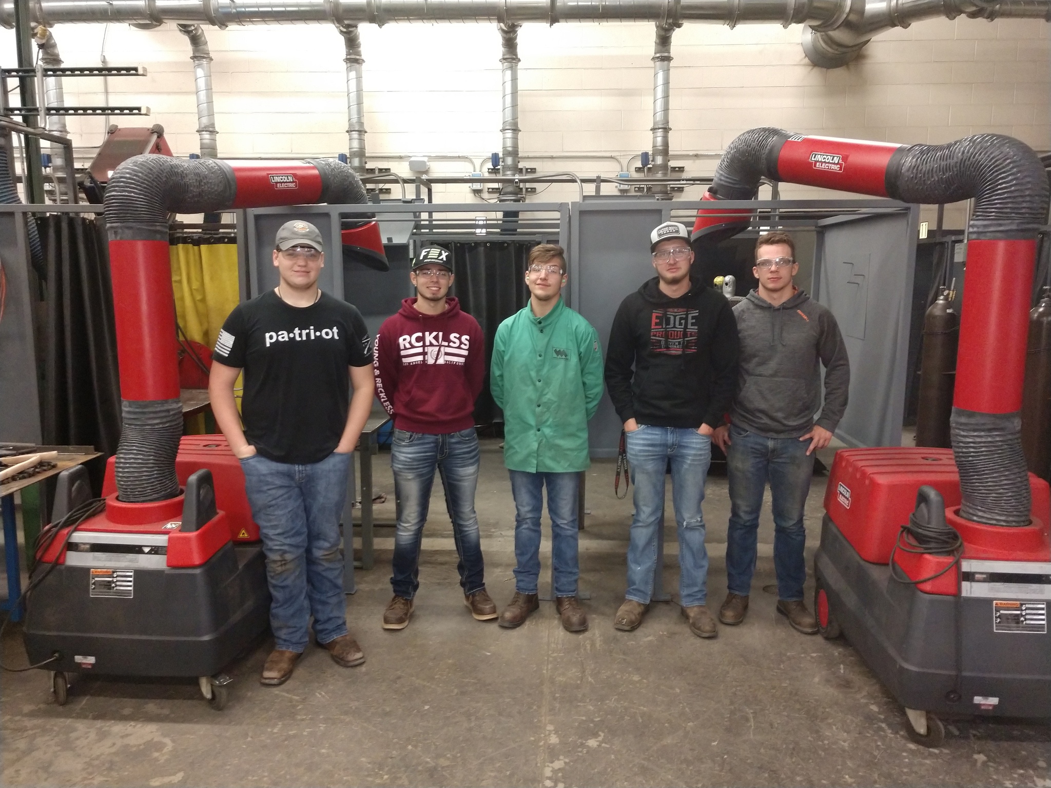Students standing next to the two new welding booths that they fabricated.