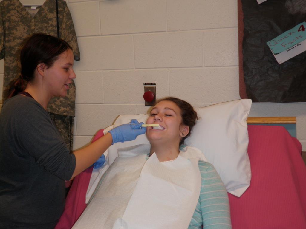 A health student practices brushing someone's teeth.