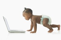 Baby on all fours looking at a computer